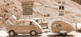 altmodisches Auto mit Anhänger und Schildern im Hintergrund